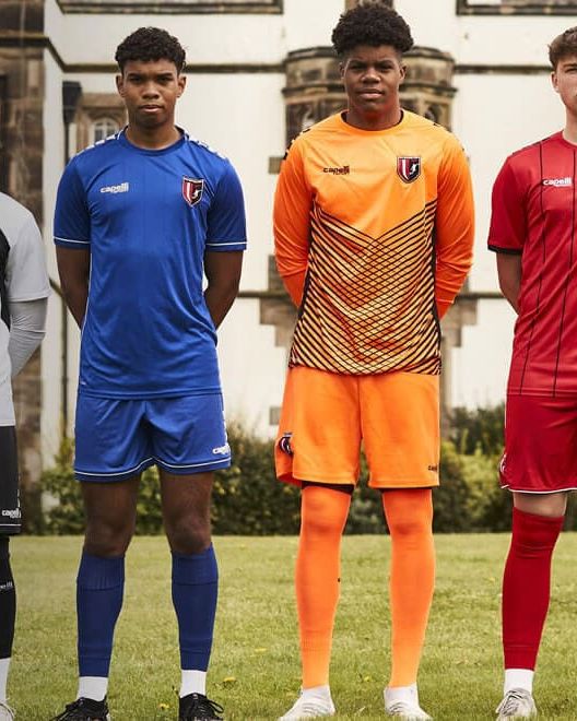 A player in a goalkeeper kit outside an English manor house