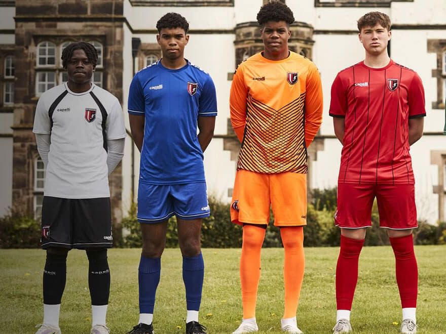 Five players in different kits outside an English manor house